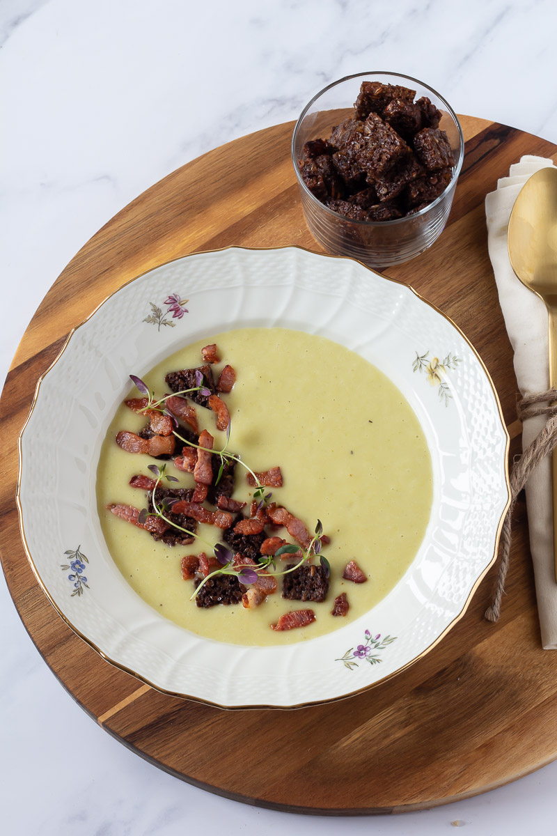Kartoffelsuppe med porre - en skøn suppe med kartofler og porre serveret i en dyb tallerken med blomster og guldkant.