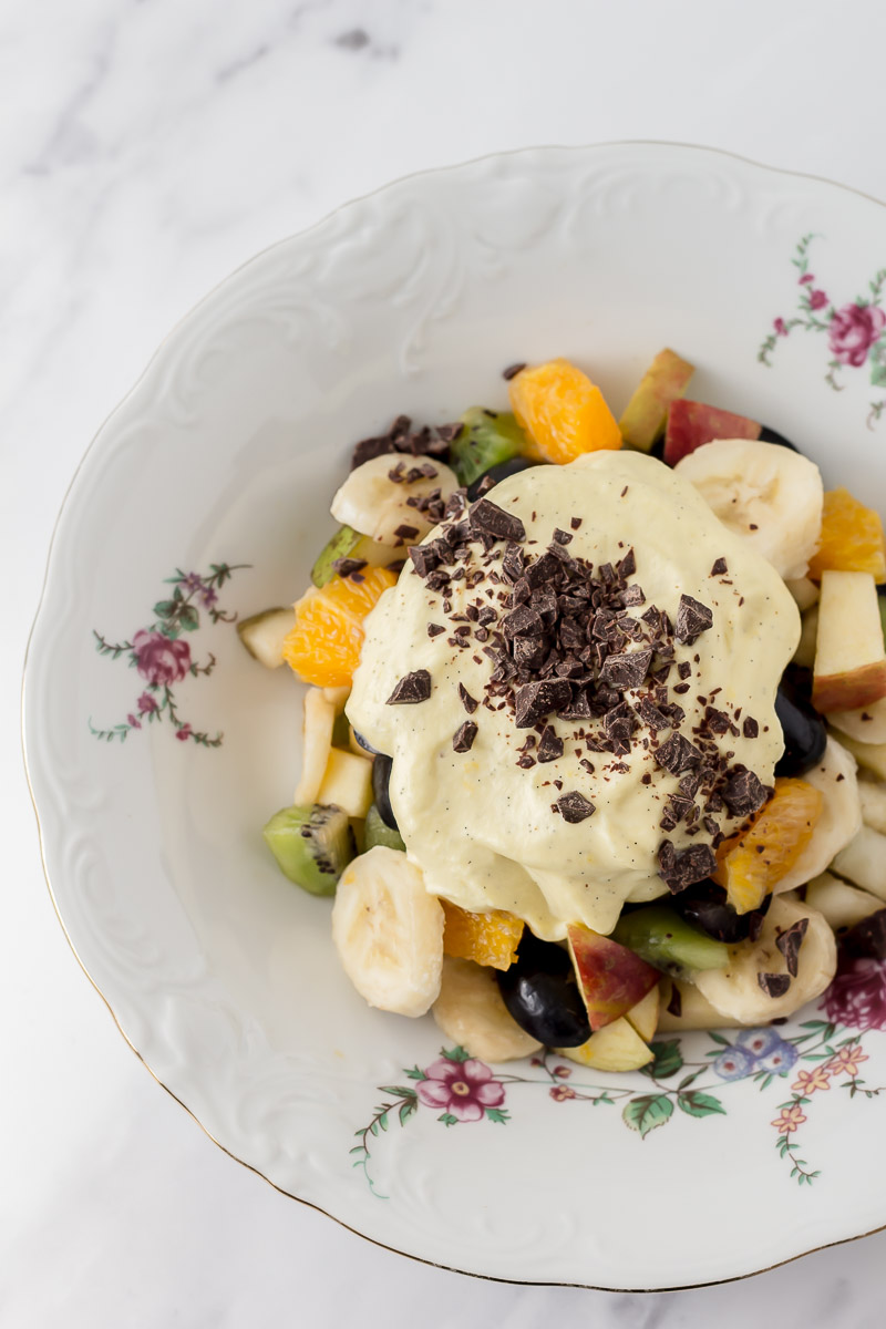 Frugtsalat med råcreme og mørk chokolade i en dyb tallerken
